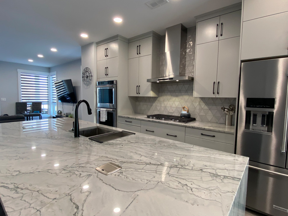 Idéer för att renovera ett mellanstort funkis grå linjärt grått kök och matrum, med en undermonterad diskho, släta luckor, grå skåp, granitbänkskiva, grått stänkskydd, stänkskydd i keramik, rostfria vitvaror, vinylgolv, en köksö och grått golv