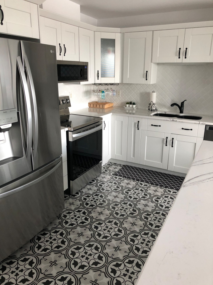Eat-in kitchen - mid-sized transitional l-shaped ceramic tile and black floor eat-in kitchen idea with an undermount sink, shaker cabinets, white cabinets, quartz countertops, white backsplash, ceramic backsplash, stainless steel appliances, an island and white countertops