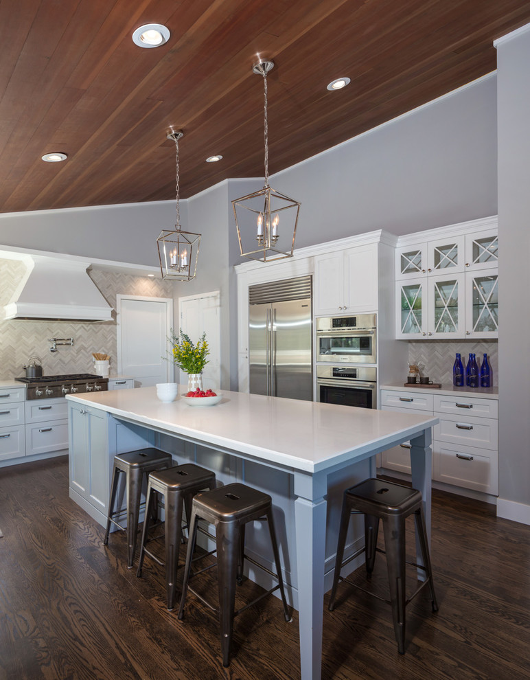 This is an example of a large transitional eat-in kitchen in San Francisco with a farmhouse sink, shaker cabinets, white cabinets, quartz benchtops, grey splashback, stainless steel appliances, dark hardwood floors, with island, brown floor, mosaic tile splashback and white benchtop.