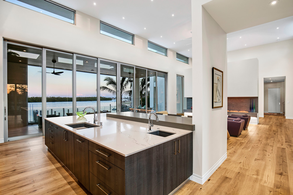 Large contemporary galley open plan kitchen in Tampa with an undermount sink, flat-panel cabinets, dark wood cabinets, quartz benchtops, grey splashback, stone slab splashback, panelled appliances, light hardwood floors, with island and brown floor.