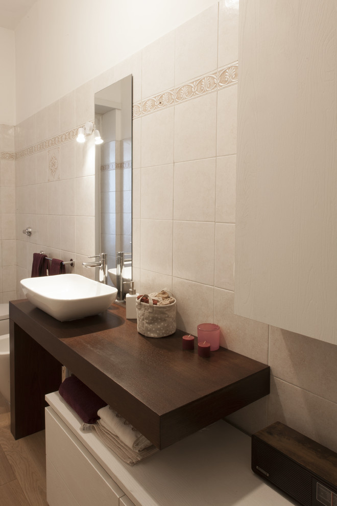 Cette image montre une salle de bain design en bois foncé de taille moyenne avec un placard sans porte, une douche d'angle, WC à poser, un carrelage beige, des carreaux de céramique, un mur beige, un sol en bois brun, une vasque et un plan de toilette en stratifié.