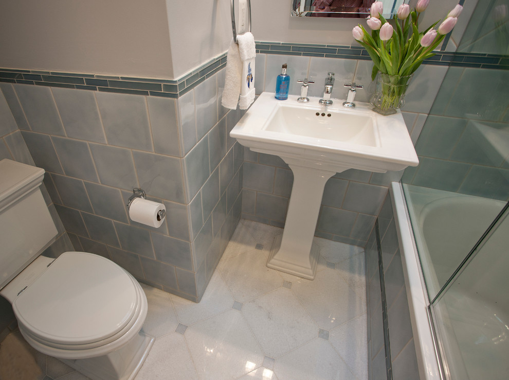 This is an example of a small traditional 3/4 bathroom in DC Metro with a pedestal sink, an alcove tub, a shower/bathtub combo, a two-piece toilet, blue tile, ceramic tile, marble floors, blue walls, red floor and a hinged shower door.