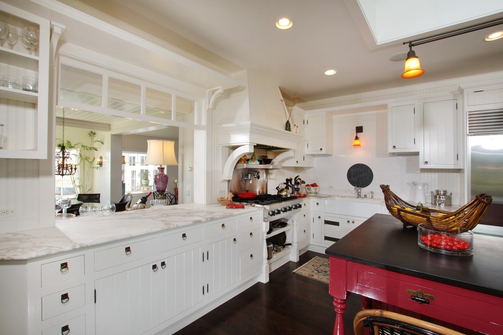 This is an example of a traditional kitchen in San Diego with stainless steel appliances, marble benchtops, a farmhouse sink, white splashback, subway tile splashback and dark hardwood floors.