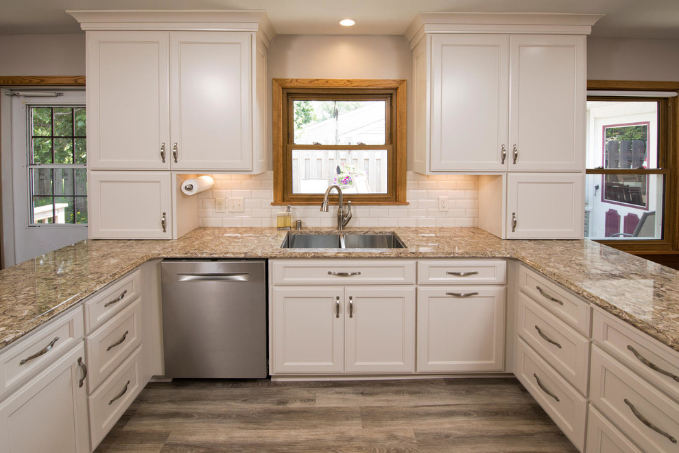 This is an example of a mid-sized traditional u-shaped eat-in kitchen in Minneapolis with a double-bowl sink, recessed-panel cabinets, white cabinets, granite benchtops, white splashback, subway tile splashback, stainless steel appliances, vinyl floors and no island.