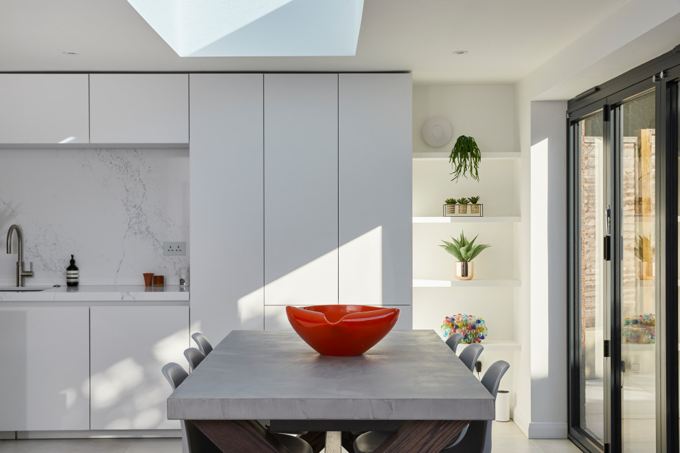 Design ideas for a large contemporary single-wall open plan kitchen in Kent with a submerged sink, flat-panel cabinets, white cabinets, engineered stone countertops, white splashback, engineered quartz splashback, stainless steel appliances, ceramic flooring, an island and white worktops.