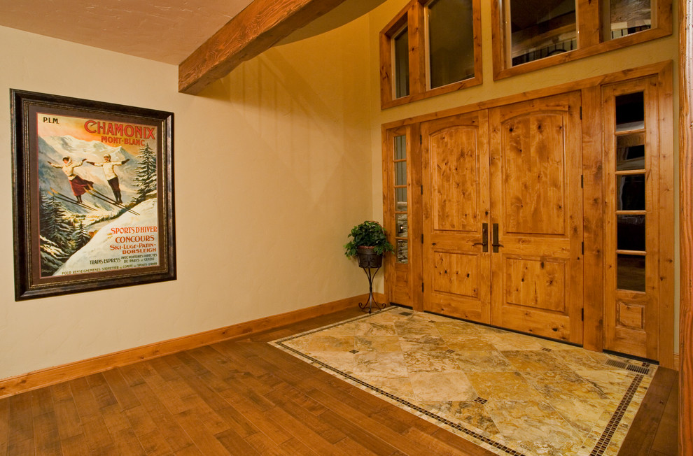 Example of a mid-sized mountain style medium tone wood floor foyer design with beige walls and a medium wood front door