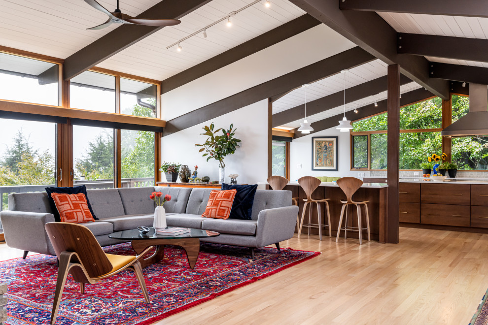 This is an example of a mid-sized midcentury open concept living room in Other with grey walls, light hardwood floors, a standard fireplace, a stone fireplace surround, beige floor and exposed beam.