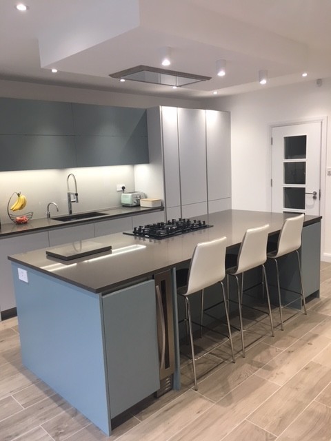 Photo of a mid-sized contemporary single-wall eat-in kitchen in London with flat-panel cabinets, blue cabinets, quartzite benchtops, white splashback and with island.