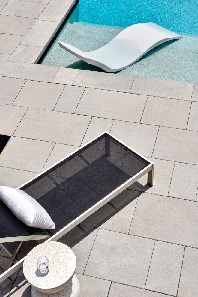 Idee per una grande piscina monocorsia moderna rettangolare dietro casa con una vasca idromassaggio e lastre di cemento