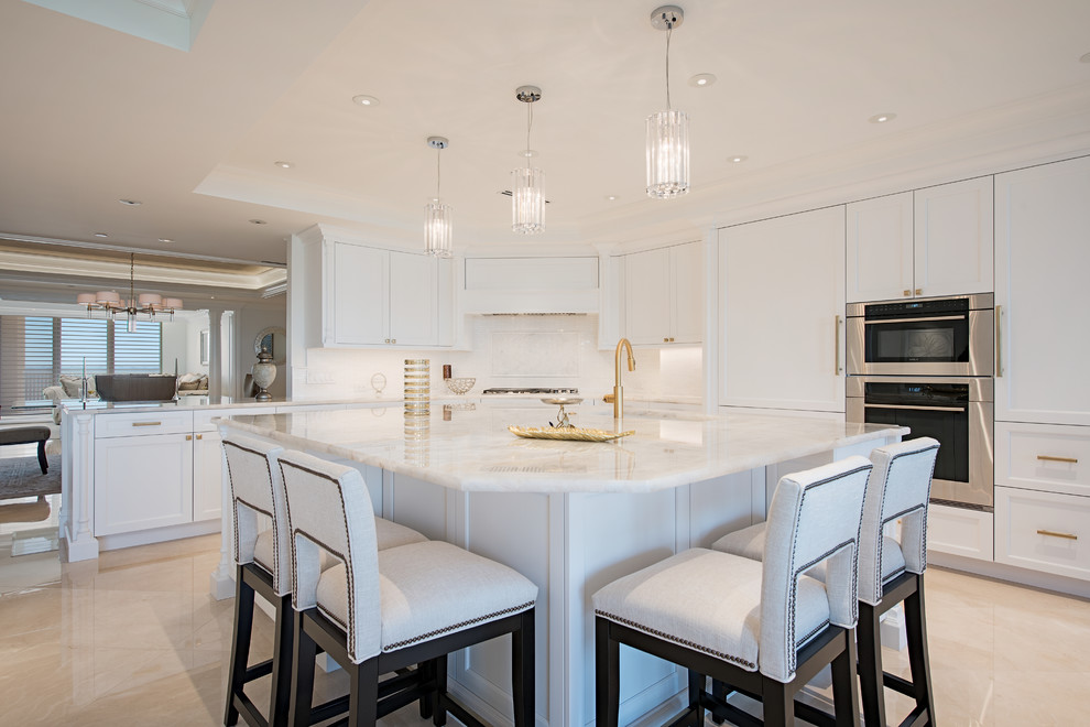 This is an example of a transitional l-shaped kitchen in Other with shaker cabinets, white cabinets, white splashback, stainless steel appliances, with island, beige floor and white benchtop.