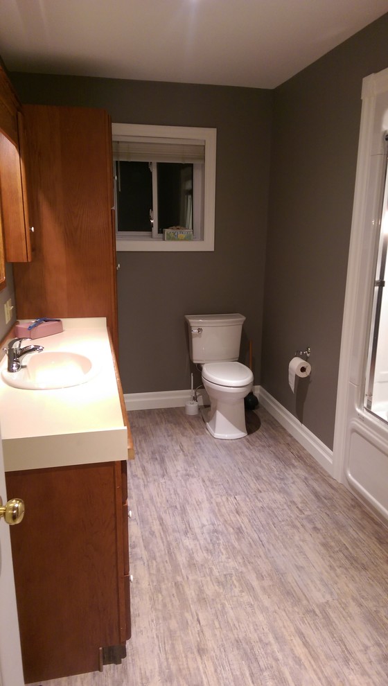 Mid-sized transitional master vinyl floor and multicolored floor alcove bathtub photo with recessed-panel cabinets, medium tone wood cabinets, a two-piece toilet, gray walls, laminate countertops and yellow countertops