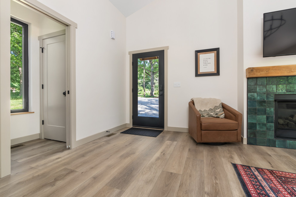 Photo of a mid-sized contemporary front door in St Louis with white walls, vinyl floors, a single front door, a black front door, brown floor and vaulted.