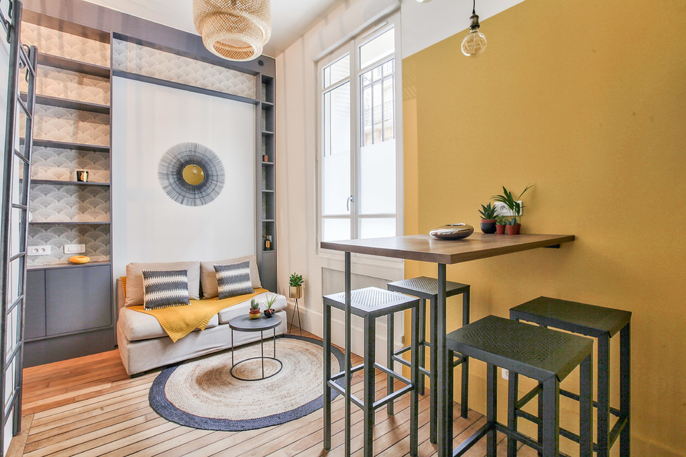 Design ideas for a mid-sized industrial loft-style living room in Paris with yellow walls, medium hardwood floors, no fireplace, brown floor, a library and a wall-mounted tv.
