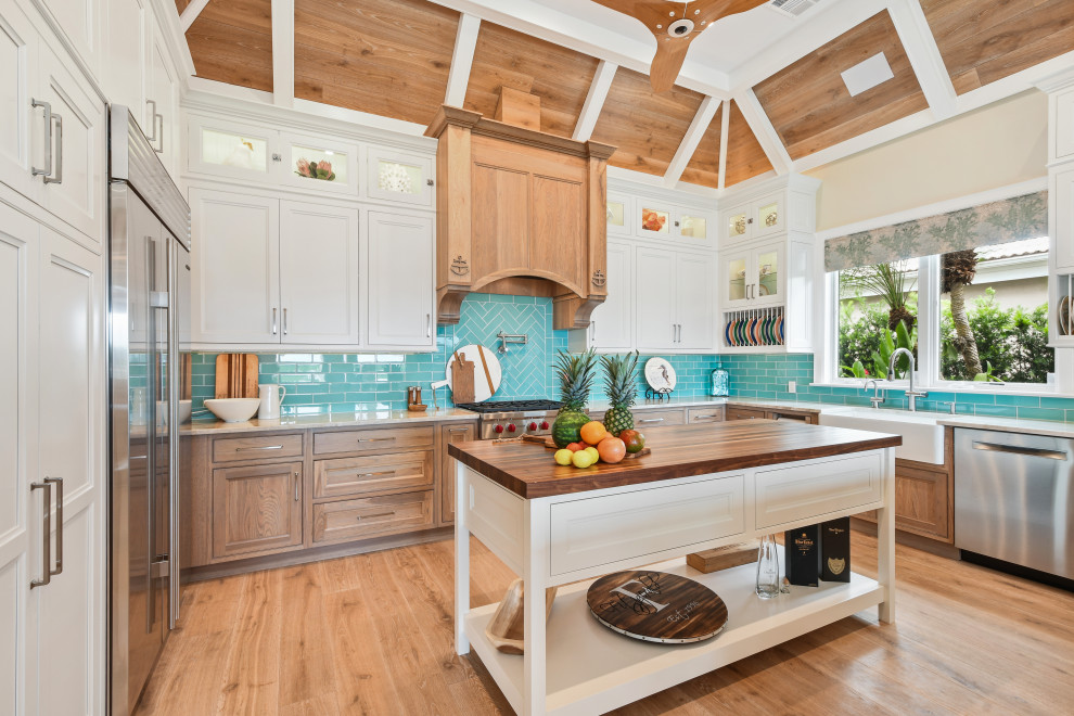 Inspiration for a large tropical u-shaped open plan kitchen in Other with an undermount sink, beaded inset cabinets, white cabinets, quartzite benchtops, blue splashback, glass tile splashback, stainless steel appliances, light hardwood floors, multiple islands, brown floor, beige benchtop and wood.