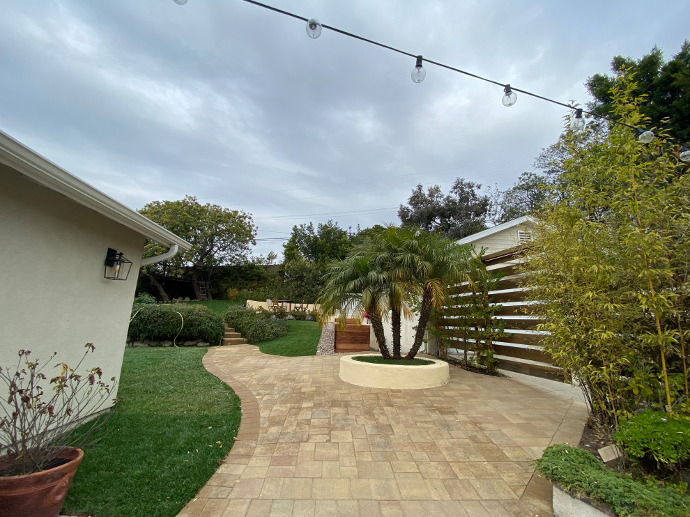 Expansive tropical backyard full sun formal garden in Los Angeles with with raised garden bed, concrete pavers and a wood fence for spring.