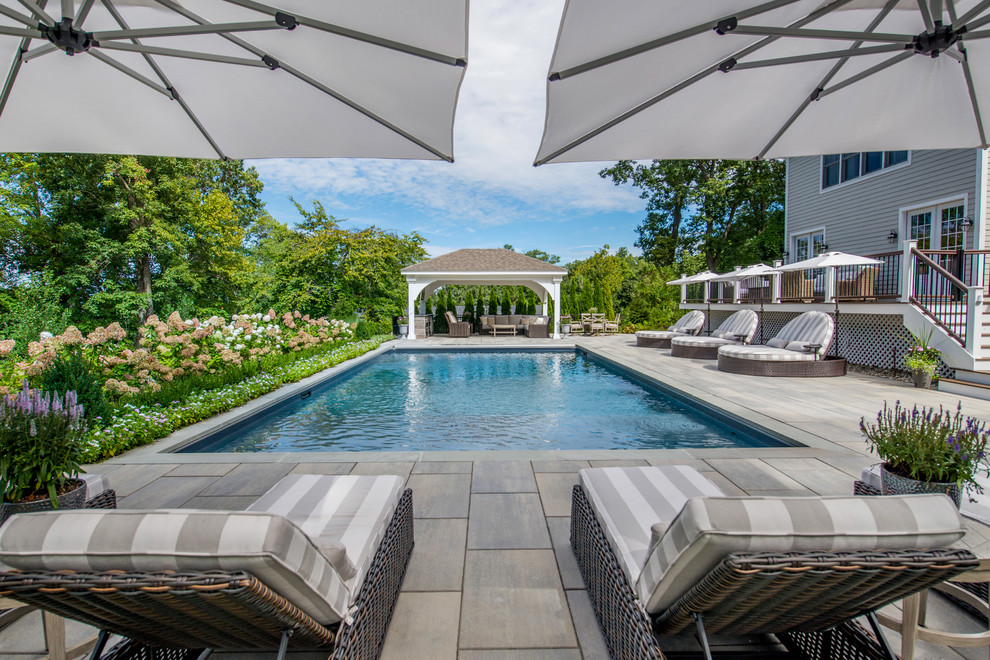 Design ideas for a mid-sized traditional rectangular pool in New York with natural stone pavers.