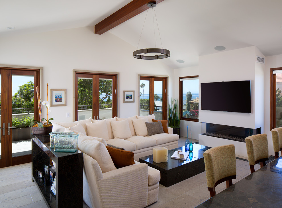Mid-sized transitional open concept family room in San Diego with white walls, a ribbon fireplace, a wall-mounted tv, limestone floors and a plaster fireplace surround.