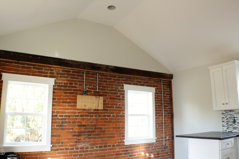 Inspiration for a small contemporary single-wall medium tone wood floor open concept kitchen remodel with an undermount sink, recessed-panel cabinets, white cabinets, granite countertops, gray backsplash, glass tile backsplash, stainless steel appliances and a peninsula