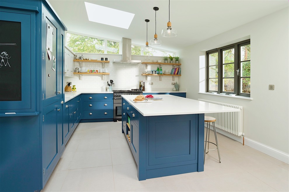 Design ideas for a mid-sized transitional kitchen in Hertfordshire with recessed-panel cabinets, blue cabinets, blue splashback, with island and grey floor.