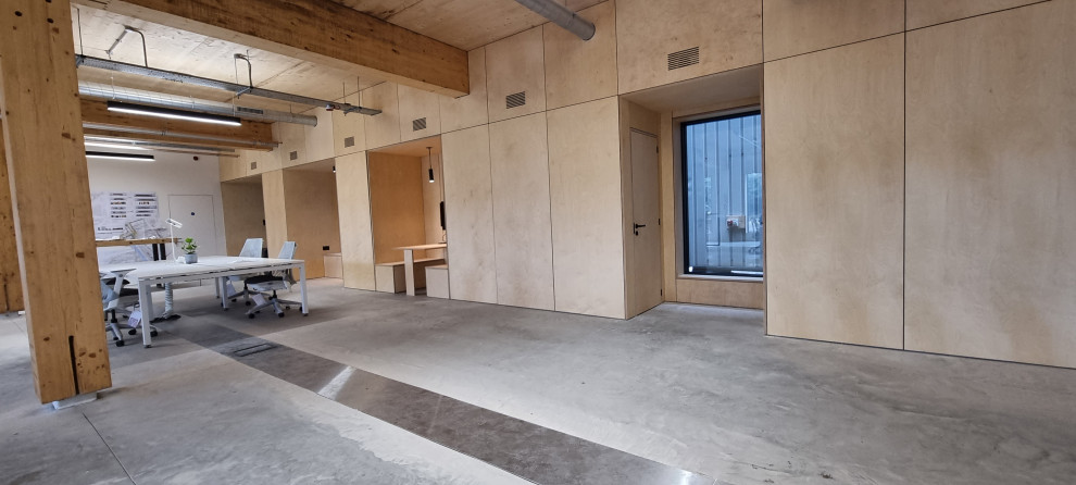 Diseño de despacho industrial grande con paredes blancas, suelo de cemento y suelo gris