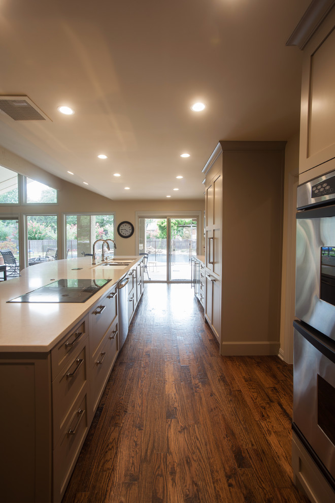 Open concept kitchen - large contemporary medium tone wood floor and brown floor open concept kitchen idea with an undermount sink, shaker cabinets, beige cabinets, quartzite countertops, white backsplash, mosaic tile backsplash, stainless steel appliances and an island