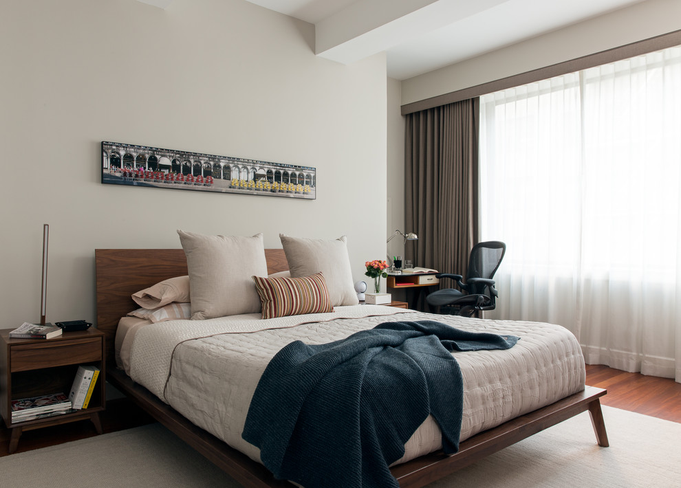 Photo of a midcentury bedroom in New York with beige walls and medium hardwood floors.