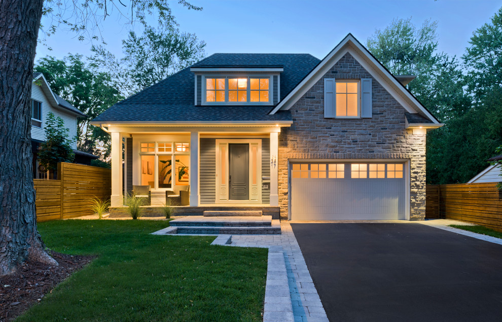 Design ideas for a mid-sized arts and crafts two-storey grey exterior in Toronto with stone veneer and a gable roof.