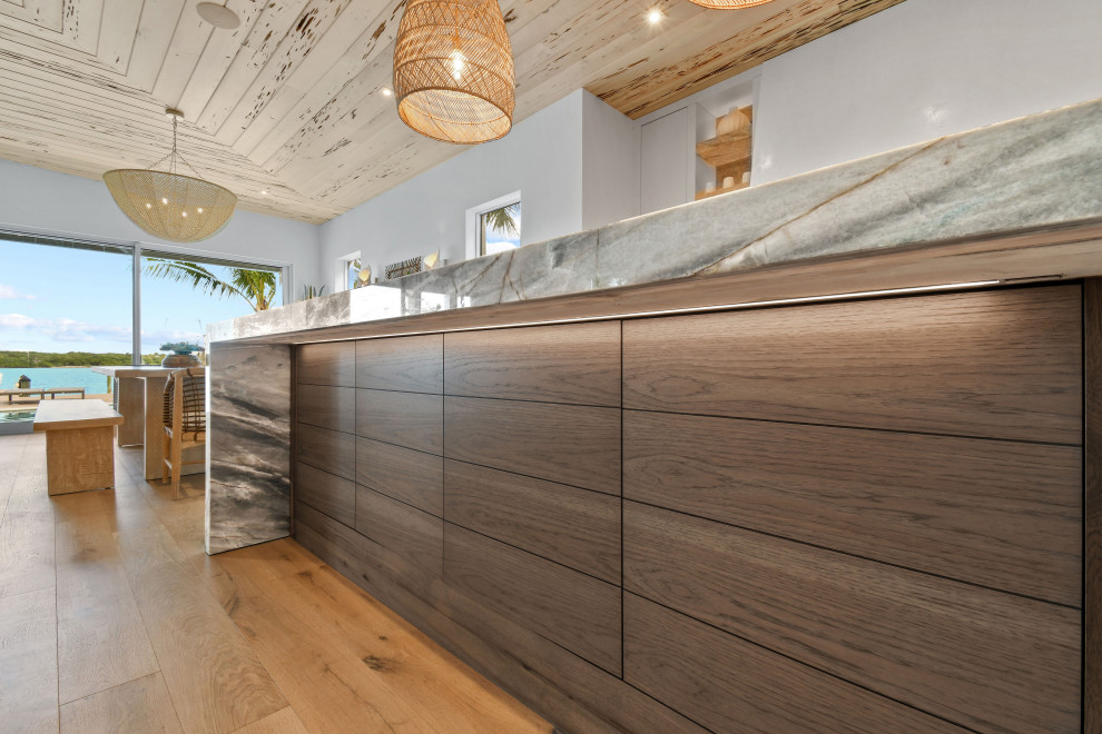 This is an example of a medium sized beach style l-shaped open plan kitchen in Other with distressed cabinets, quartz worktops, integrated appliances and an island.