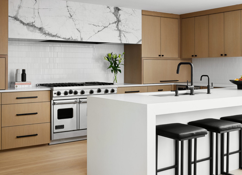 Inspiration for a contemporary u-shaped kitchen in Chicago with flat-panel cabinets, white splashback, mosaic tiled splashback, stainless steel appliances and a breakfast bar.
