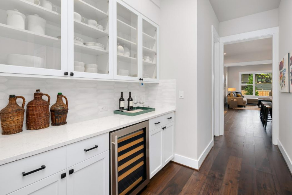 Photo of an expansive arts and crafts l-shaped open plan kitchen in Seattle with an undermount sink, shaker cabinets, white cabinets, quartz benchtops, white splashback, ceramic splashback, stainless steel appliances, dark hardwood floors, with island, brown floor and white benchtop.