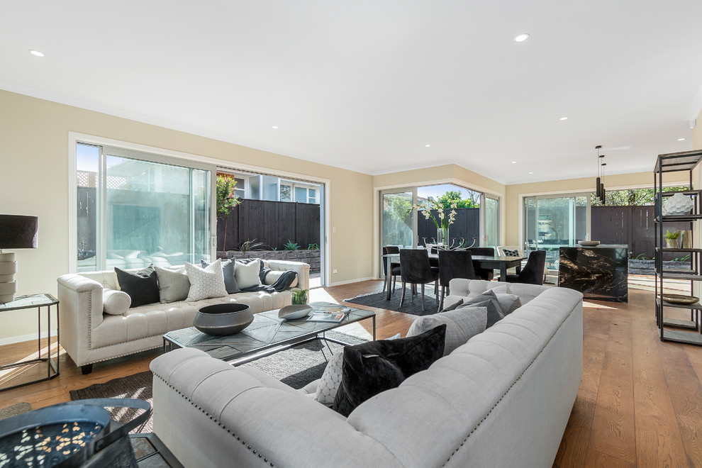 Photo of a large contemporary open concept living room in Auckland with light hardwood floors and a standard fireplace.