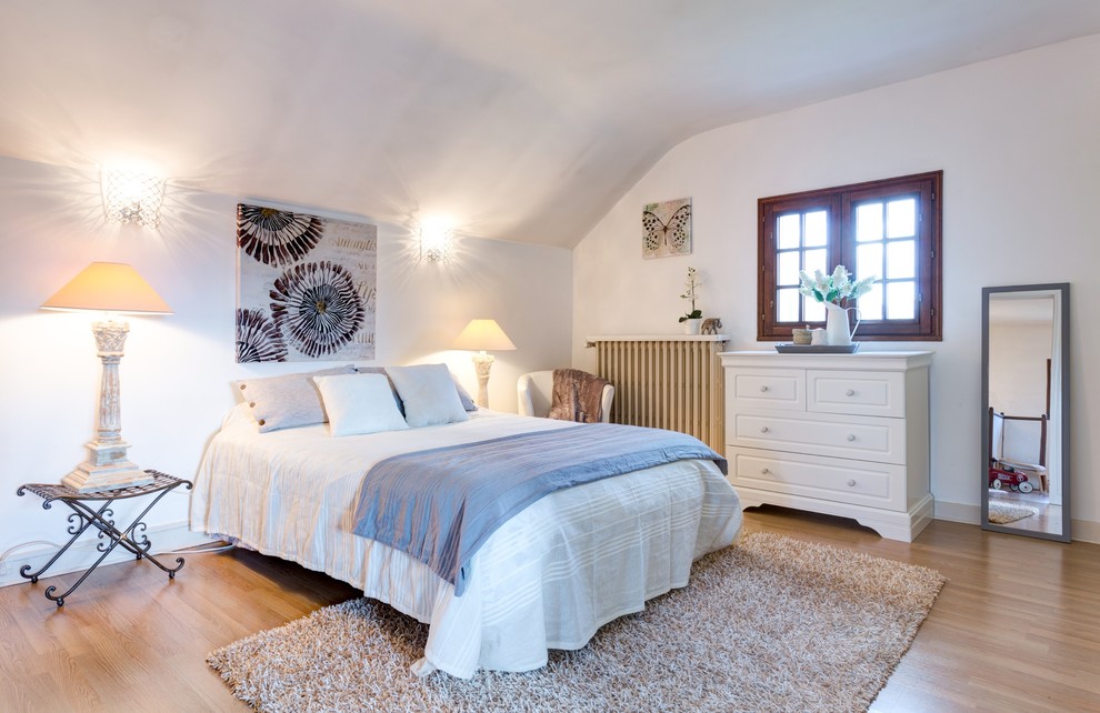 Inspiration for a large transitional master bedroom in Rennes with white walls and light hardwood floors.