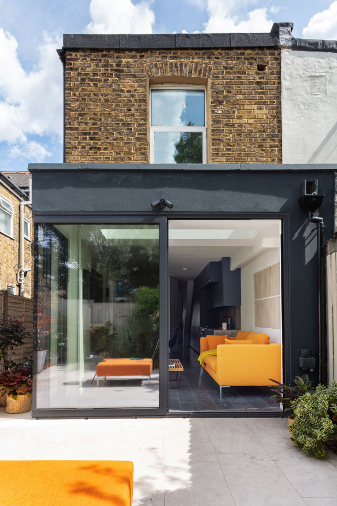 Design ideas for a small contemporary one-storey stucco black apartment exterior in London with a flat roof.