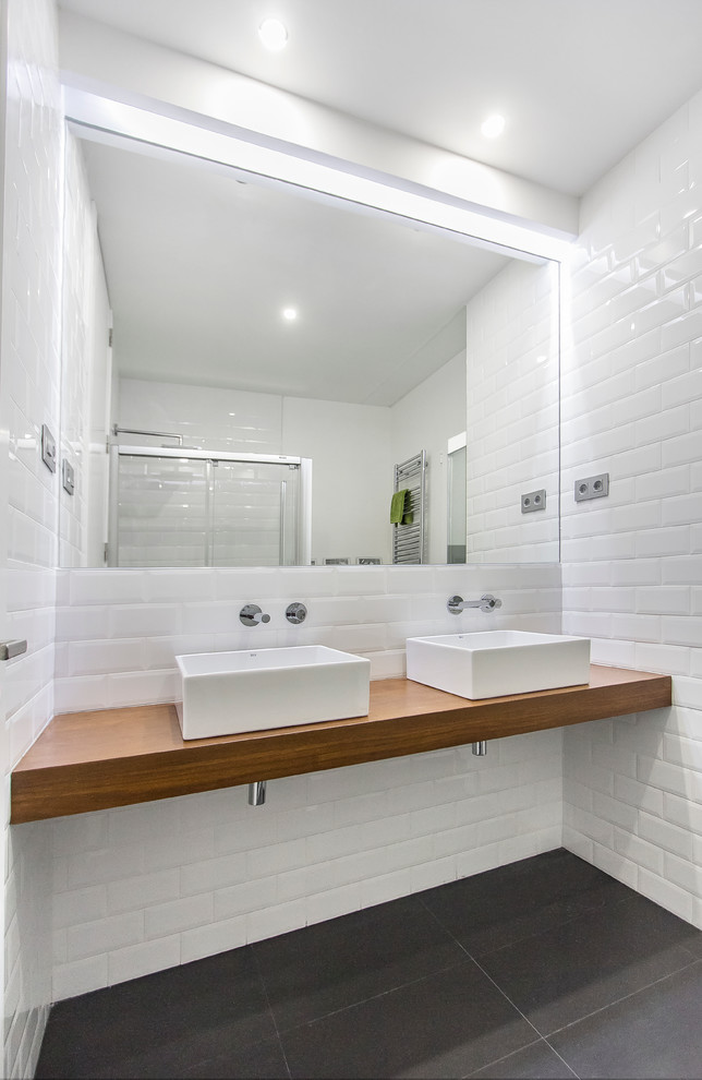 This is an example of a mid-sized scandinavian master bathroom in Madrid with open cabinets, medium wood cabinets, a curbless shower, a wall-mount toilet, white tile, ceramic tile, white walls, ceramic floors, a vessel sink and wood benchtops.