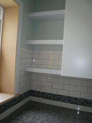 Inspiration for a mid-sized transitional galley concrete floor open concept kitchen remodel in St Louis with a farmhouse sink, shaker cabinets, medium tone wood cabinets, granite countertops, white backsplash, ceramic backsplash, stainless steel appliances and an island