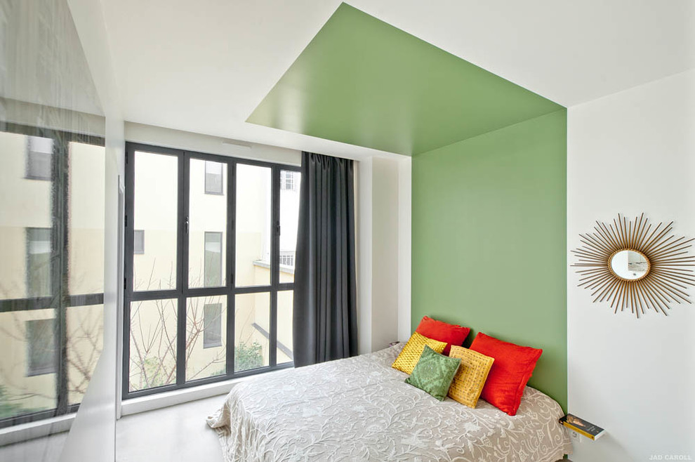 This is an example of a mid-sized modern master bedroom in Paris with green walls and concrete floors.
