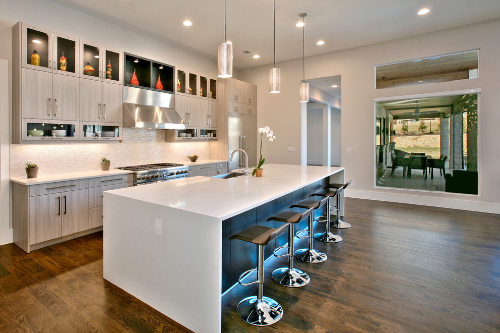 Photo of a mid-sized contemporary l-shaped eat-in kitchen in Dallas with a farmhouse sink, flat-panel cabinets, light wood cabinets, quartzite benchtops, white splashback, stone tile splashback, stainless steel appliances, medium hardwood floors and with island.