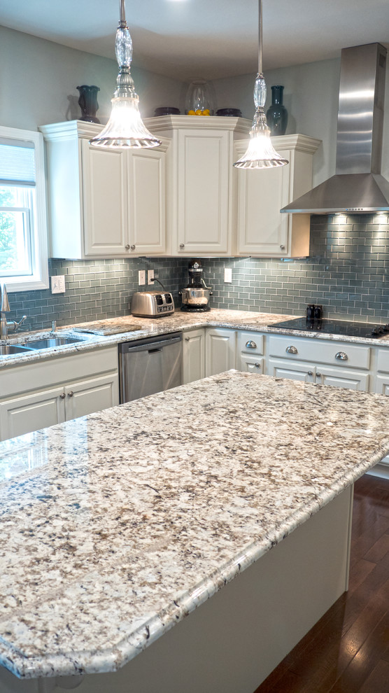 Inspiration for a transitional u-shaped medium tone wood floor eat-in kitchen remodel with a double-bowl sink, raised-panel cabinets, white cabinets, granite countertops, blue backsplash, glass tile backsplash, stainless steel appliances and an island