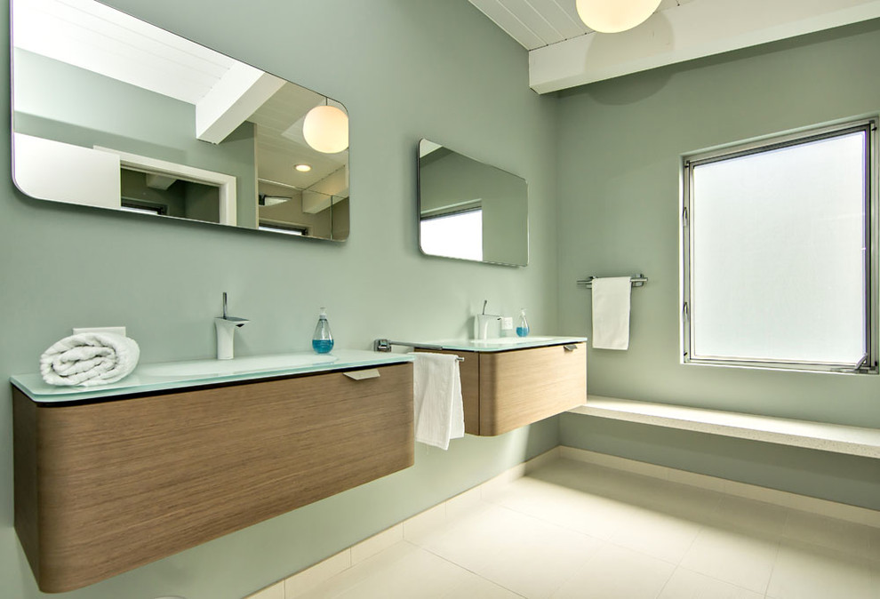 Midcentury bathroom in San Francisco with flat-panel cabinets, medium wood cabinets, glass benchtops and beige tile.