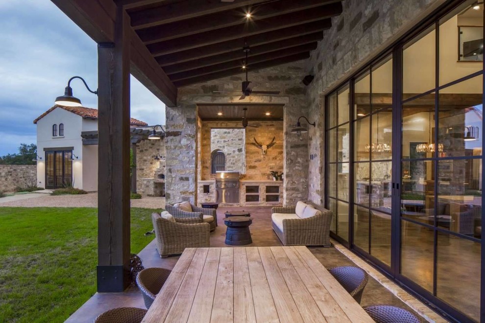 Photo of a large mediterranean backyard patio in Austin with an outdoor kitchen, concrete slab and a roof extension.