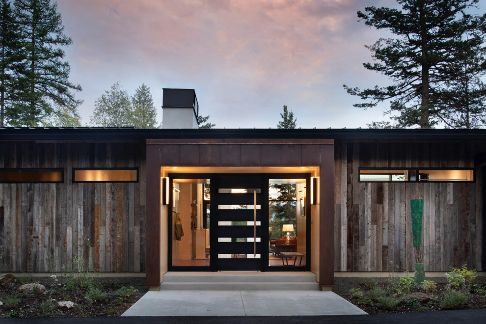 Foto della facciata di una casa grande contemporanea a due piani con rivestimento in legno, copertura in metallo o lamiera e tetto nero