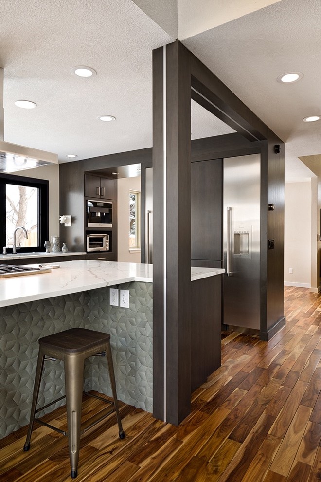 Eat-in kitchen - mid-sized modern l-shaped medium tone wood floor and brown floor eat-in kitchen idea in Denver with a single-bowl sink, flat-panel cabinets, dark wood cabinets, quartz countertops, gray backsplash, stone tile backsplash, stainless steel appliances, an island and white countertops