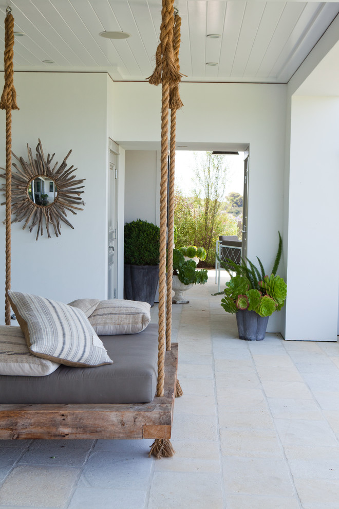 This is an example of a beach style verandah in Orange County with a container garden and a roof extension.