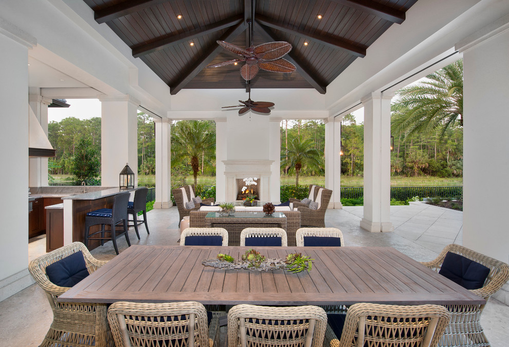 Example of a huge island style backyard stone patio kitchen design in Miami with a roof extension