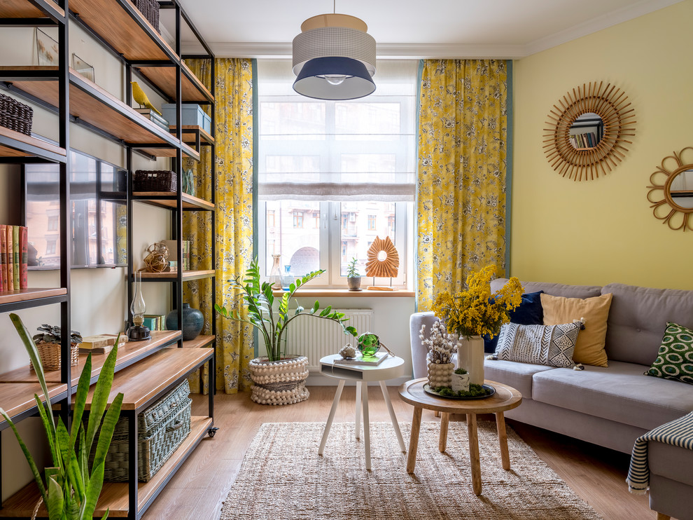 Photo of a mid-sized beach style enclosed living room in Moscow with a library, yellow walls, medium hardwood floors, no fireplace, a wall-mounted tv and beige floor.