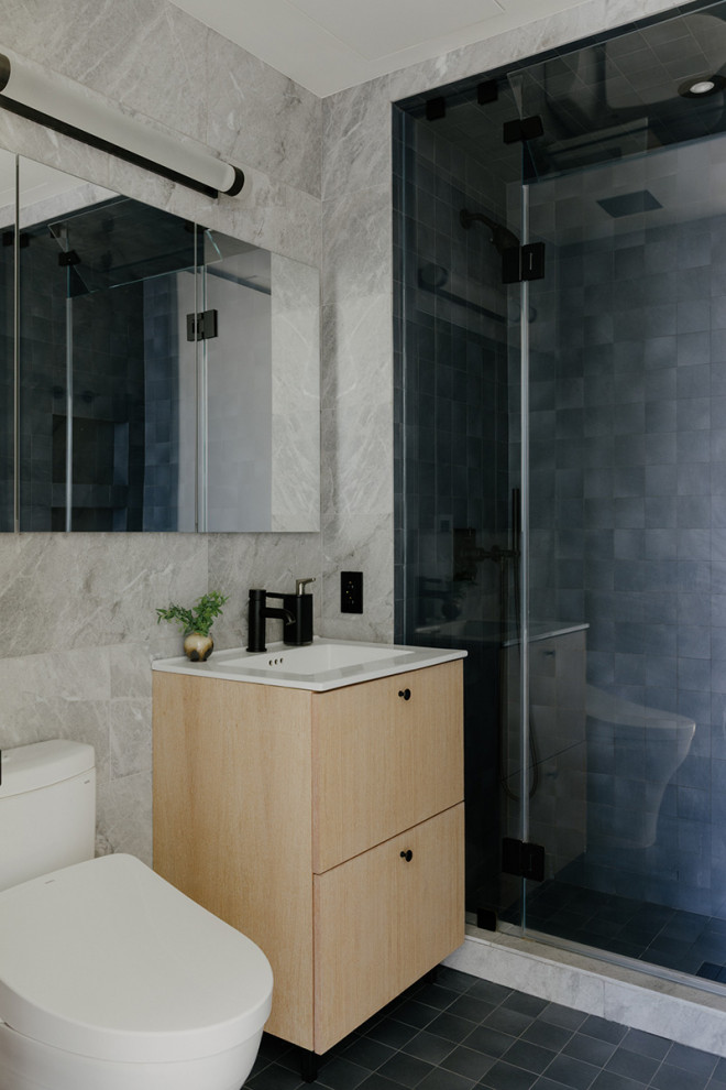 Small minimalist 3/4 black tile and cement tile cement tile floor, black floor and single-sink alcove shower photo in New York with flat-panel cabinets, light wood cabinets, a one-piece toilet, gray walls, an integrated sink, a hinged shower door, white countertops and a floating vanity