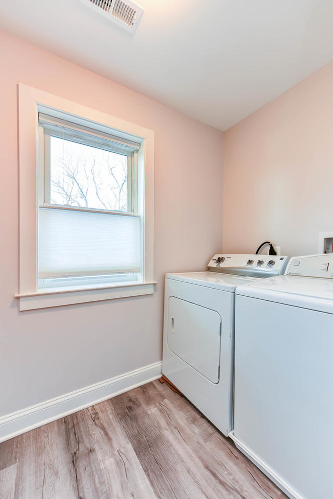 Photo of a mid-sized traditional single-wall utility room with beige walls and a side-by-side washer and dryer.