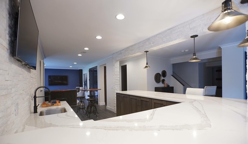 This is an example of a large industrial u-shaped wet bar in DC Metro with vinyl floors, an undermount sink, distressed cabinets, quartzite benchtops, white splashback, stone tile splashback and black floor.