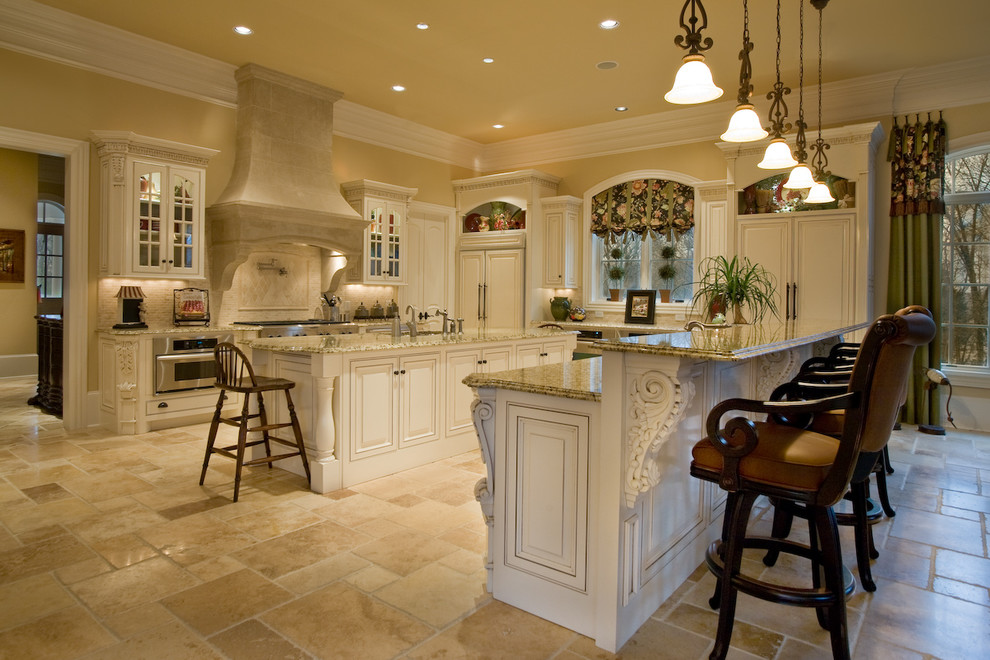 Inspiration for a large transitional l-shaped ceramic tile eat-in kitchen remodel in Nashville with an undermount sink, raised-panel cabinets, white cabinets, granite countertops, beige backsplash, ceramic backsplash, stainless steel appliances and two islands