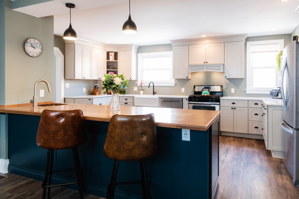 Large midcentury u-shaped separate kitchen in New York with an undermount sink, shaker cabinets, blue cabinets, wood benchtops, white splashback, subway tile splashback, stainless steel appliances, light hardwood floors, with island, grey floor and multi-coloured benchtop.